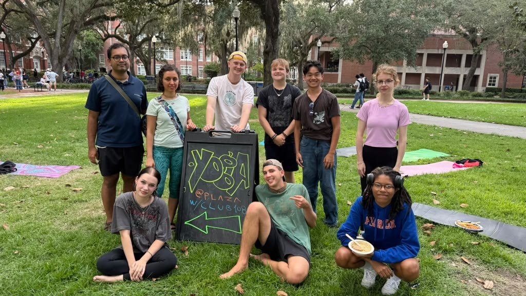 Club108 members gathered beside a yoga sign on campus