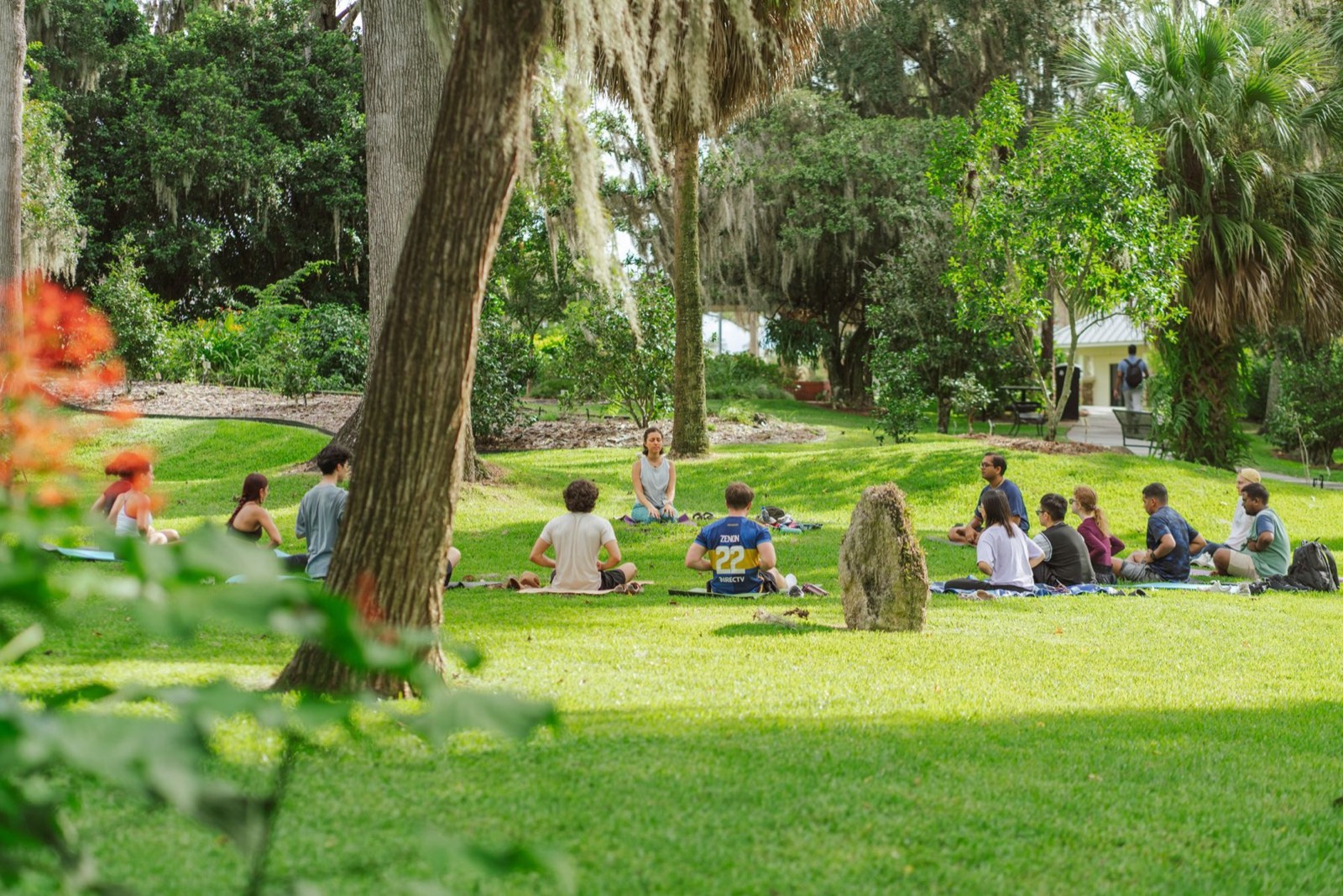 Club108 participants sitting together in a circle on a green lawn